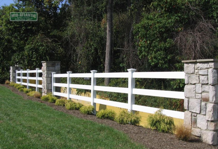 White vinyl paddock style fence in between stone pillars. Pasadena Maryland