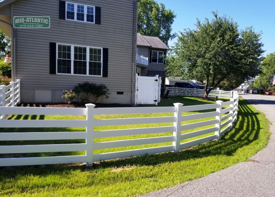 This White vinyl 5 rail paddock style fence follows the radius of the road.
