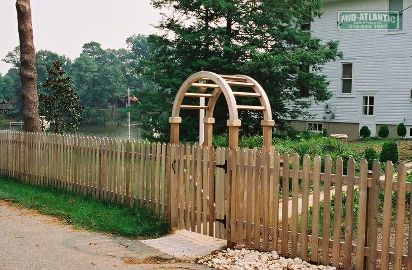 Dog eared picket wood fence with a cedar round top arbor is a great look for any property.