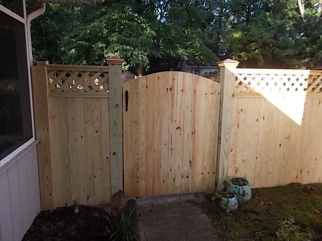 Vertical board privacy fence with lattice accent was this customers choice including a solid style gate with round top to allow access to their back yard.