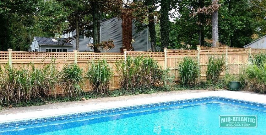 Notice how the fence is stair stepped on this property in Arnold Maryland. The board and batten style fence with square lattice accent was a great choice for this pool.